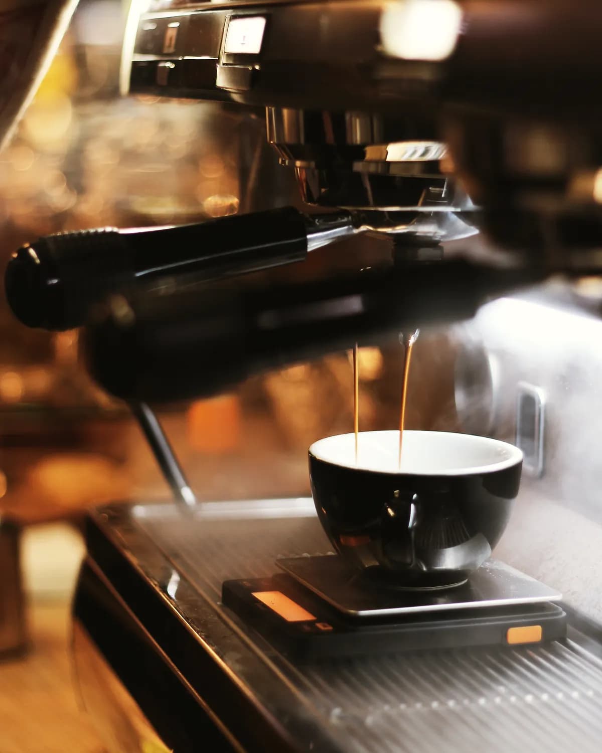Espresso care curge într-o ceașcă neagră, pe un cântar sub espressor